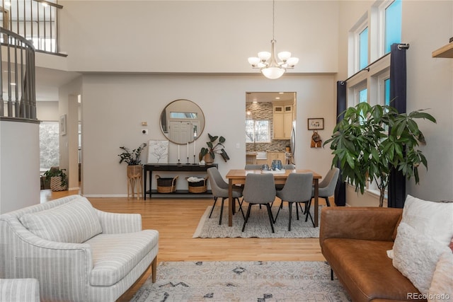 dining room with a chandelier, a towering ceiling, and wood finished floors