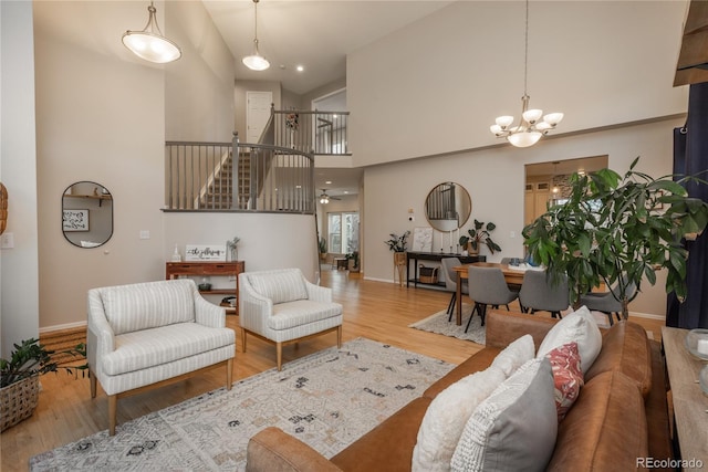 living room featuring high vaulted ceiling, stairway, baseboards, and wood finished floors