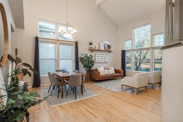 dining space featuring high vaulted ceiling, wood finished floors, and a notable chandelier