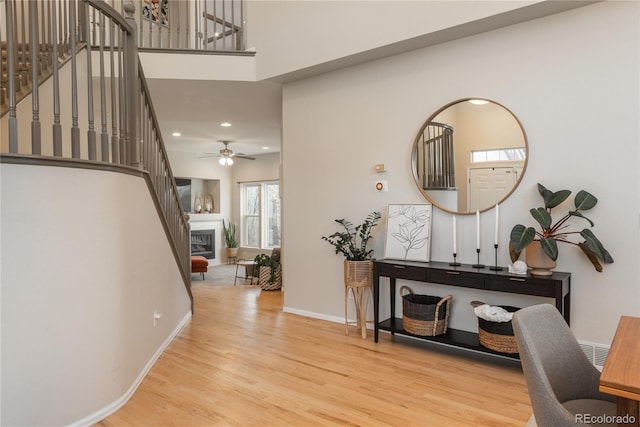 entrance foyer with baseboards, stairway, wood finished floors, and a glass covered fireplace