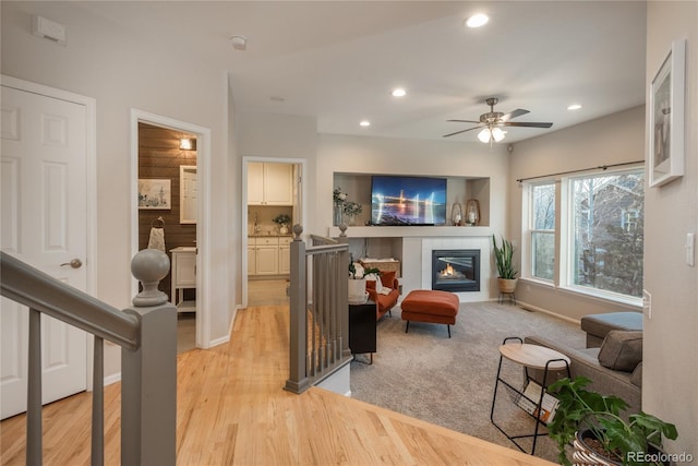 living room with light wood-type flooring, baseboards, a tiled fireplace, and recessed lighting