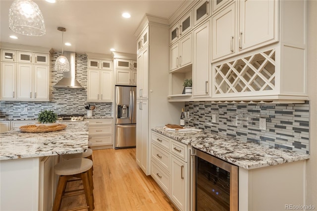 kitchen with beverage cooler, light wood-style floors, a kitchen breakfast bar, wall chimney range hood, and stainless steel fridge