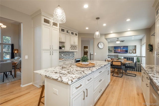 kitchen featuring open floor plan, a kitchen island, backsplash, and light wood-style flooring