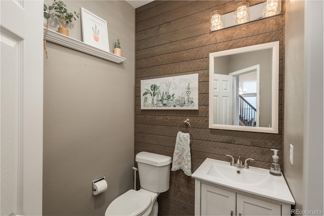 bathroom featuring wood walls, vanity, and toilet