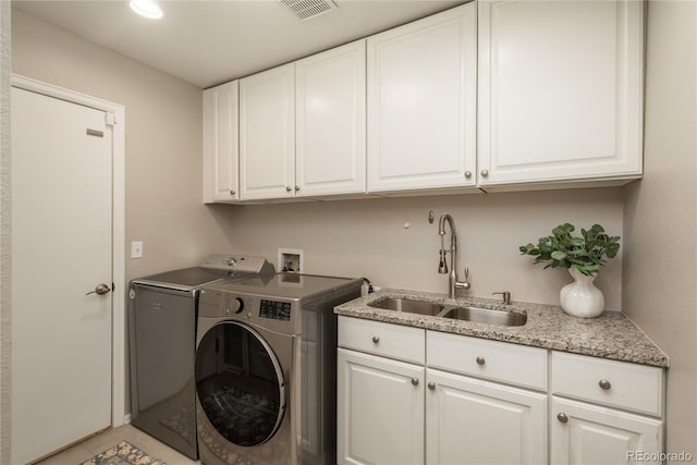 clothes washing area featuring visible vents, independent washer and dryer, a sink, and cabinet space