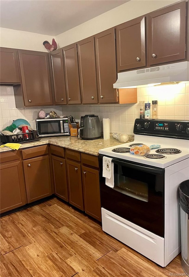 kitchen featuring light wood-type flooring, backsplash, dark brown cabinets, and white range with electric stovetop