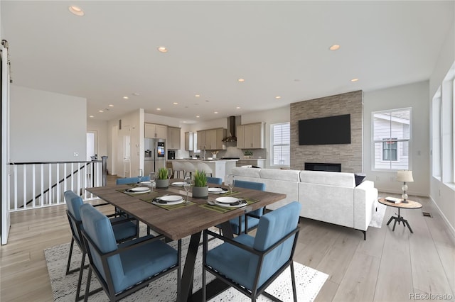 dining space featuring light wood-type flooring, a wealth of natural light, sink, and a stone fireplace