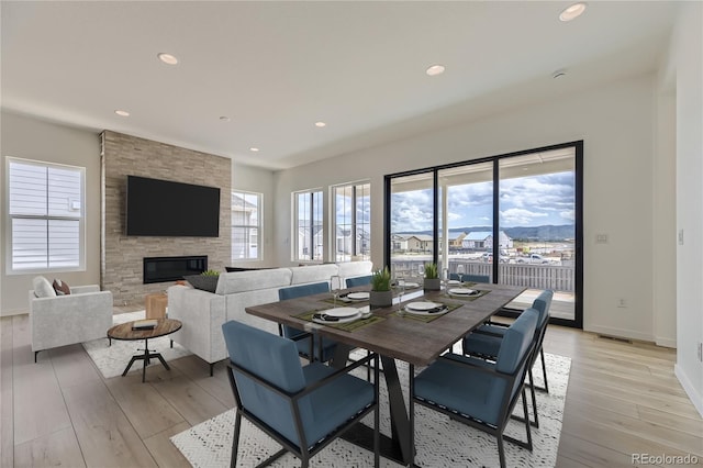 dining room featuring light hardwood / wood-style floors and a stone fireplace