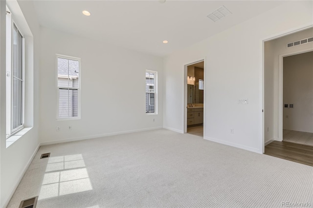 unfurnished bedroom with light colored carpet and ensuite bath