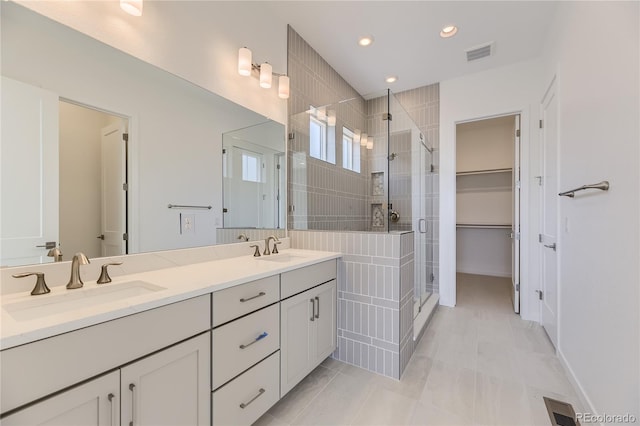 bathroom featuring tile patterned flooring, a shower with shower door, and vanity