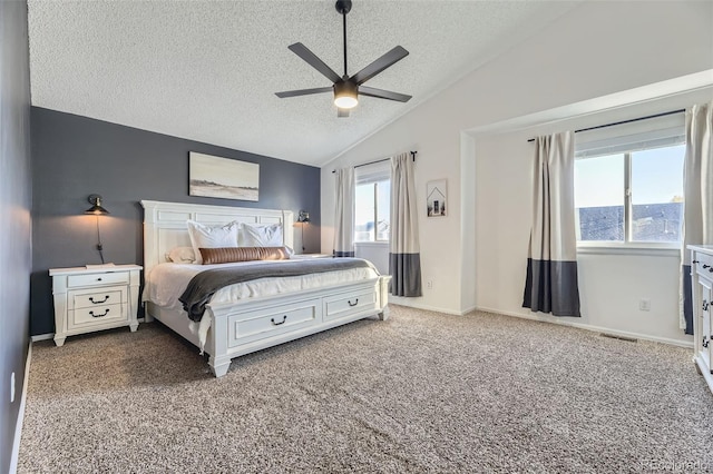 carpeted bedroom with a textured ceiling, ceiling fan, multiple windows, and vaulted ceiling