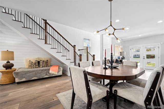 dining space featuring light wood finished floors, a notable chandelier, stairs, and a wealth of natural light