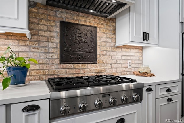 kitchen featuring stainless steel gas stovetop, light countertops, tasteful backsplash, and white cabinets