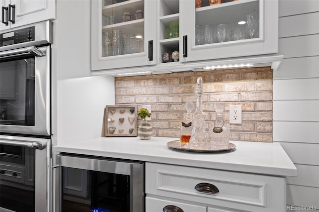 bar featuring backsplash, beverage cooler, and stainless steel double oven