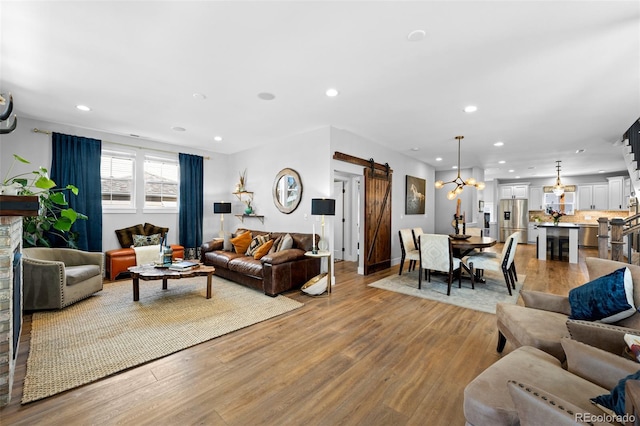 living area featuring recessed lighting, a chandelier, a barn door, and light wood finished floors