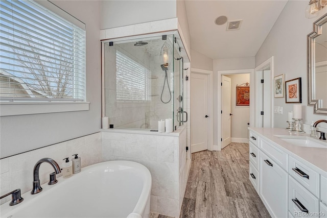 full bath featuring visible vents, a stall shower, wood finished floors, vanity, and a soaking tub