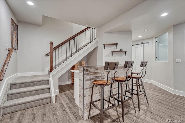 stairs with a barn door, baseboards, recessed lighting, and wood finished floors