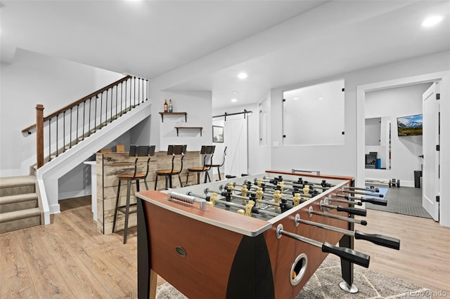 playroom with light wood-style floors, a barn door, baseboards, and recessed lighting