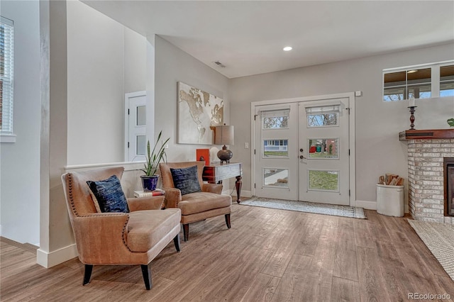 sitting room featuring wood finished floors, a fireplace, baseboards, recessed lighting, and french doors
