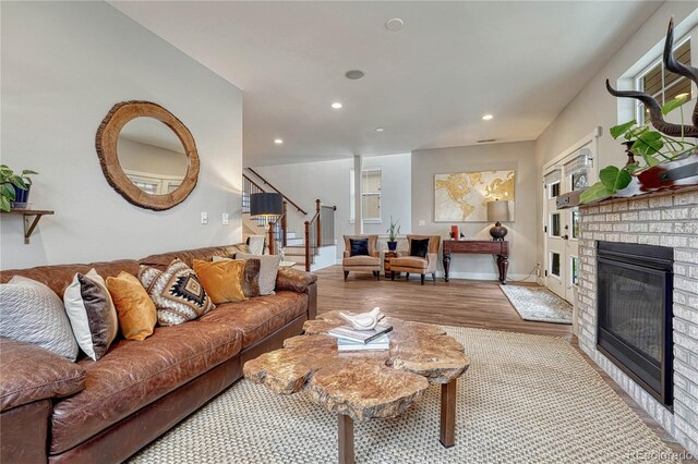 living room with a brick fireplace, recessed lighting, wood finished floors, and stairway