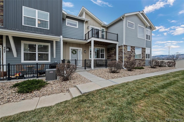 view of property featuring a front yard, a balcony, and central AC