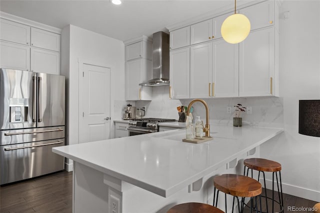 kitchen featuring white cabinets, wall chimney range hood, and appliances with stainless steel finishes