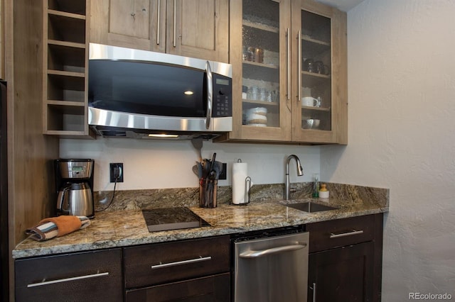 bar featuring light stone countertops, appliances with stainless steel finishes, sink, and dark brown cabinetry