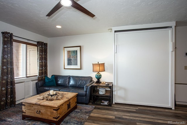 living room featuring ceiling fan, dark hardwood / wood-style floors, and a textured ceiling