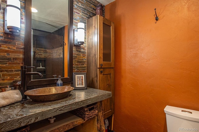 bathroom featuring sink, a wood stove, toilet, and brick wall