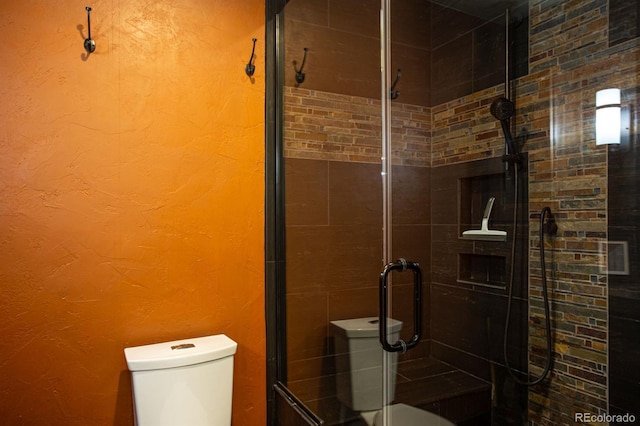 bathroom featuring a shower with shower door and toilet