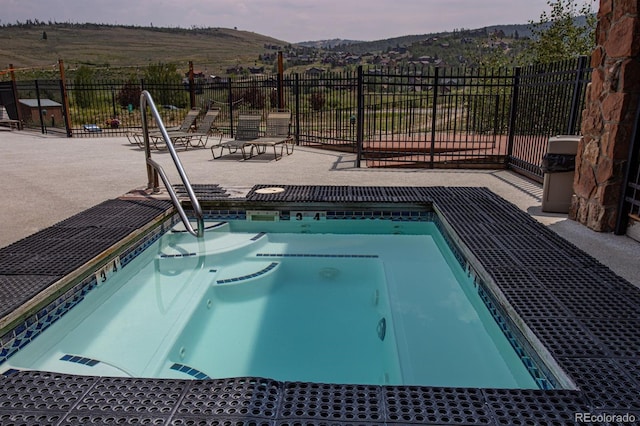 pool at dusk with a patio and an in ground hot tub