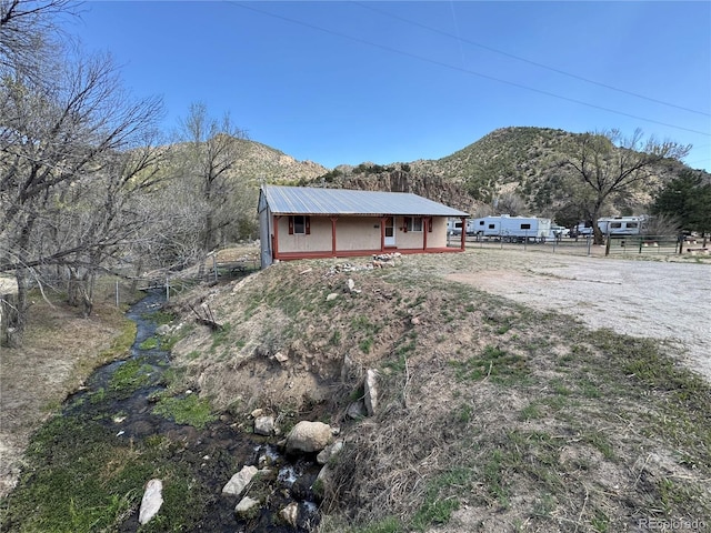 view of home's exterior featuring a mountain view, fence, and metal roof