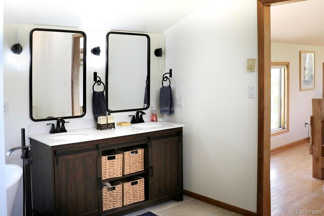 bathroom featuring dual vanity, a washtub, and wood-type flooring