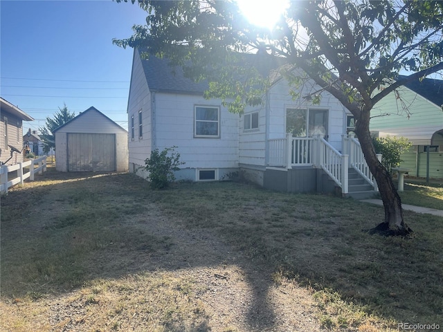 rear view of property with a storage unit and a yard