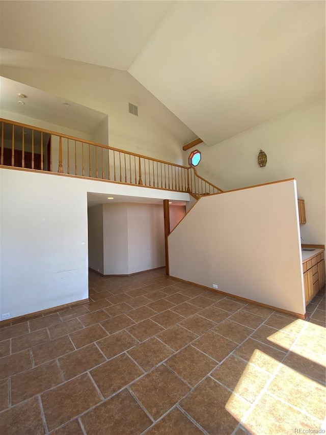 spare room featuring stairs, high vaulted ceiling, and visible vents