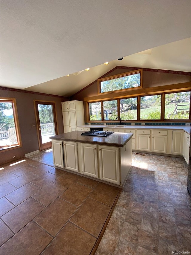 kitchen with plenty of natural light, a kitchen island, vaulted ceiling, and black cooktop