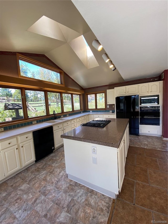 kitchen featuring a sink, white cabinets, black appliances, and lofted ceiling with skylight