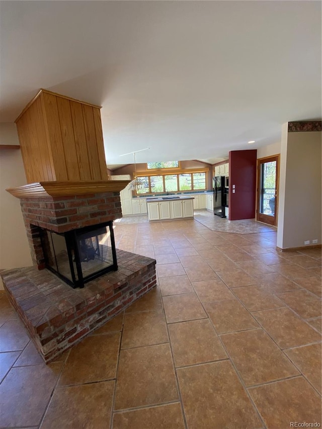 living area featuring tile patterned floors, vaulted ceiling, baseboards, and a fireplace