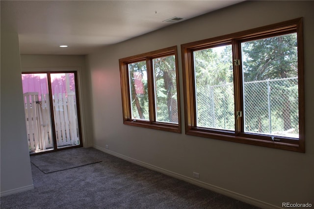 spare room featuring dark carpet, recessed lighting, baseboards, and visible vents