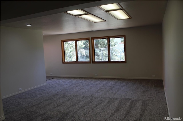 spare room with baseboards and dark colored carpet