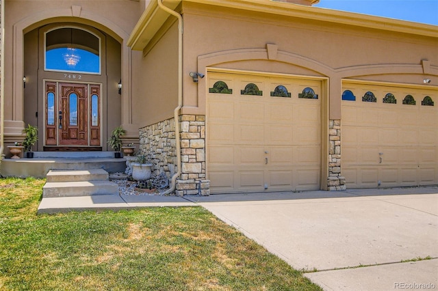 7482 Routt Ln, Arvada, CO 80005 - doorway to property featuring concrete driveway, an attached garage, stone siding, and stucco siding