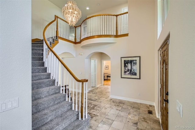 7482 Routt Ln, Arvada, CO 80005 - entrance foyer featuring arched walkways, stairway, a high ceiling, and a chandelier