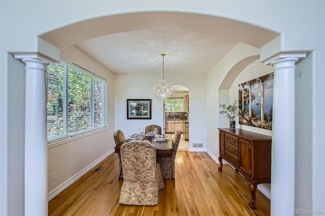 7482 Routt Ln, Arvada, CO 80005 - dining room with light wood-style floors, arched walkways, and a chandelier
