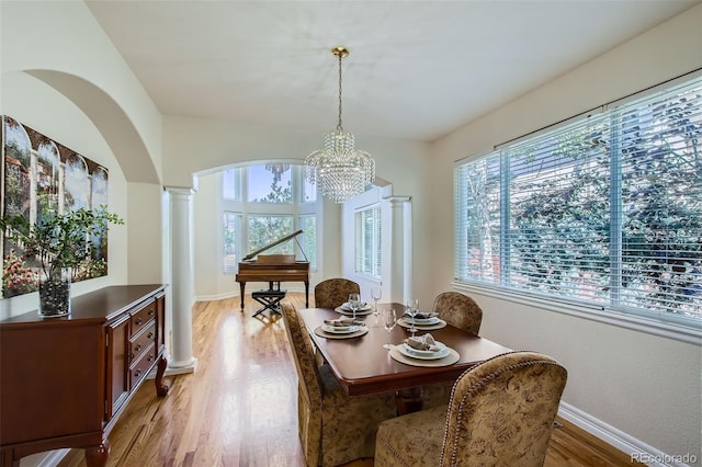 7482 Routt Ln, Arvada, CO 80005 - dining area with decorative columns, light wood-style flooring, arched walkways, and a chandelier