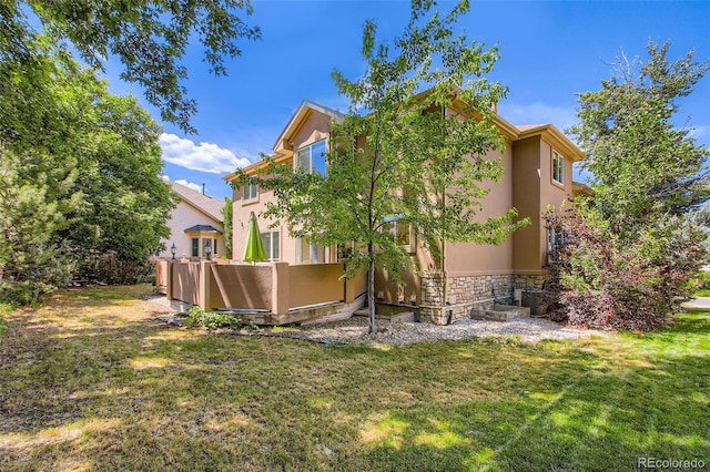 7482 Routt Ln, Arvada, CO 80005 - view of home's exterior with stucco siding, stone siding, and a yard