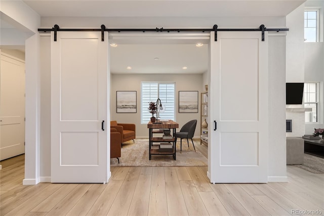 hallway featuring a barn door and light hardwood / wood-style flooring