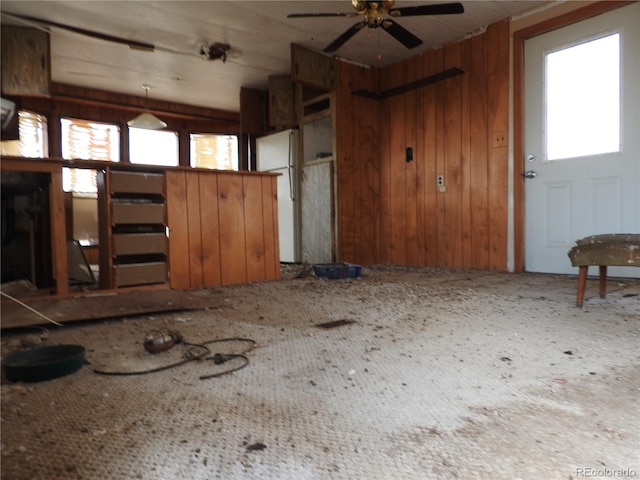 interior space featuring ceiling fan, wooden walls, lofted ceiling, and a healthy amount of sunlight