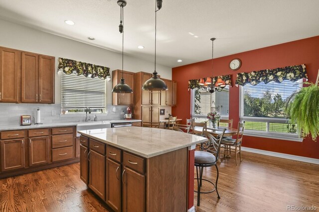 kitchen with a kitchen breakfast bar, a kitchen island, tasteful backsplash, dark wood finished floors, and a sink