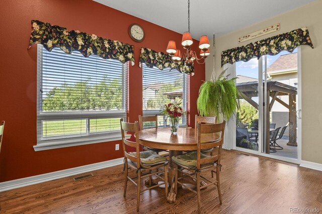 dining room featuring visible vents, baseboards, wood finished floors, and a chandelier