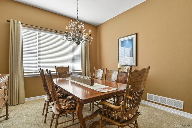 dining room featuring visible vents, baseboards, a chandelier, and light carpet
